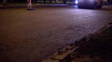 Yol çalışması. Asfalt düzeliyor. Yeni yol yüzeyi. Sokak tamiri. Asfalt silindiri. Gece sahnesi. 