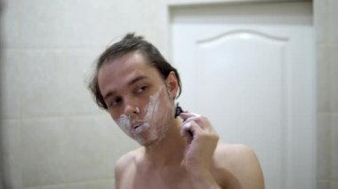 Adam banyoda aynanın önündeki beş kilit gölgesini tıraş ediyor..