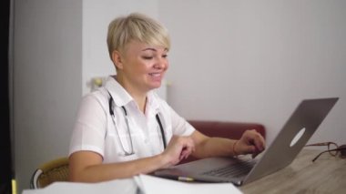The pleasant adult woman doctor is communicating with patient from home. Online clinic appointment.
