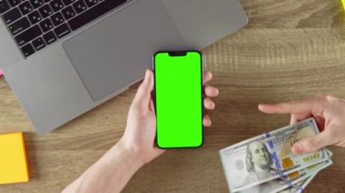 Guy is showing how easy to earn money with freelance green screen mockup chroma key. Waving american dollars.