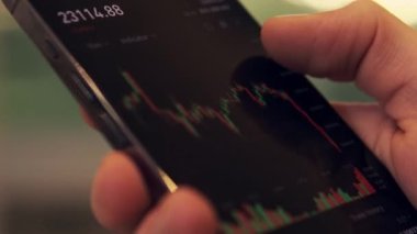  Cryptocurrency price index on the mobile phone screen. Businessman analyzing digital stock market investments. 