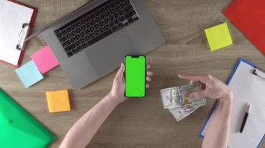 Guy is showing how easy to earn money with freelance green screen mockup chroma key. Waving american dollars. Horizontal position.