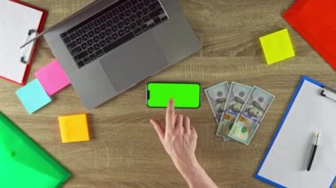 Man is sharing the method how he earned money with freelance on the phone in horizontal position mockup. 100 dollar bills on the table. American currency.