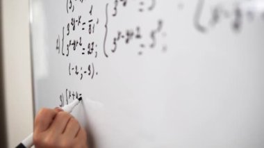 Writing the equation on the whiteboard using the marker close up.