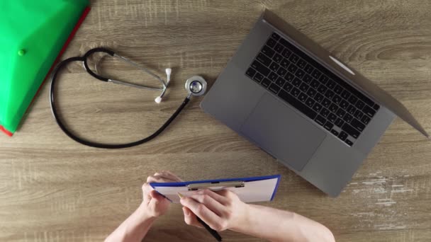 Doctor Writing Symptoms Patient Wooden Table Files Notebook Stethoscope Laptop — Video