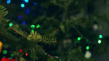 The Christmas tree with garland with lights with pile of colorful presents. 