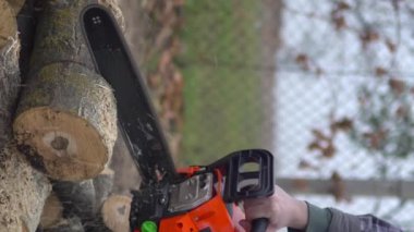 A man is a worker sawing a tree with a chainsaw. Vertical video. High quality footage