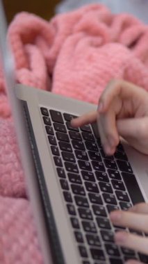 The girl at home typing on a laptop. Surfing the Internet in bed. Vertical video. High quality footage