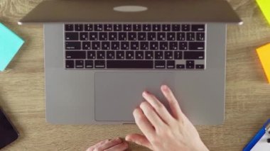 Internet user is scrolling down on the touchpad. Zoom filming. Phone, color stickers and papers on the table.