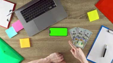 The developer is showing the programming courses green screen mockup concept. American currency. 100 dollar bills on the table.