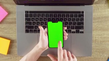 Man is showing the application green screen chroma key. Laptop and color stickers on the background.