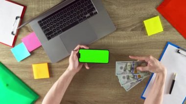 Man is sharing the app where he earned money with freelance green screen mockup.Waving 100 dollar bills. American value.