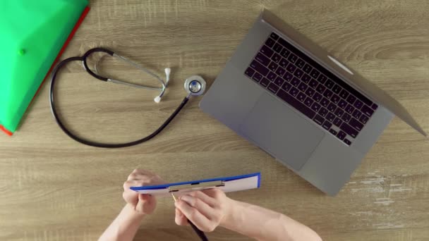 Physician Making Notes Using Pen Table View Files Notebook Stethoscope — Vídeos de Stock