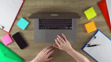Student is studying with notebook and laptop at home. Color stickers and phone on the table.