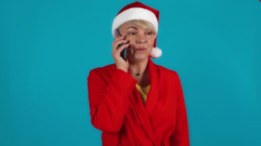  Noel Baba kostümlü kadın Xmas selamı dinliyor. Mavi arkaplan.