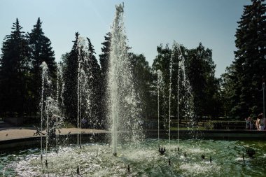 Çalışan bir çeşme ve etrafında dinlenen insanlar..