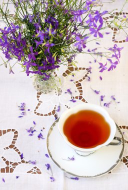 bir fincan çay ve mor kır çiçekleri