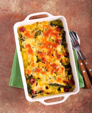 Lahana ve sosisler fırında peynirle pişirilir.