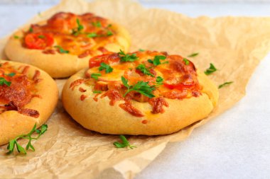 Pişirme kağıdının üzerinde ev yapımı mini pizza.