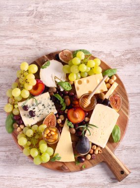 Cheese board: appetizers board with assorted cheese, fruits, honey and nuts -charcuterie board