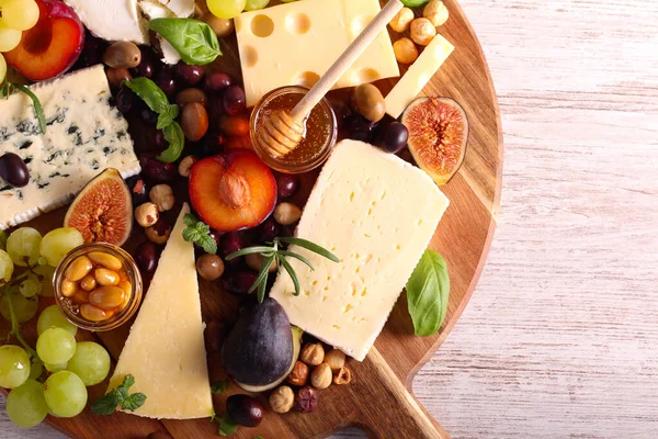 Cheese board: appetizers board with assorted cheese, fruits, honey and nuts -charcuterie board