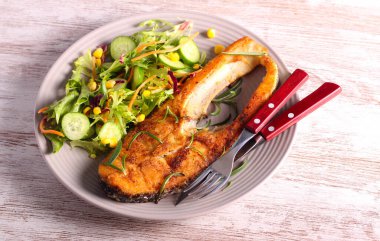 Fried perch fish with salad on plate