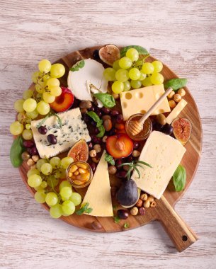 Cheese board: appetizers board with assorted cheese, fruits, honey and nuts -charcuterie board
