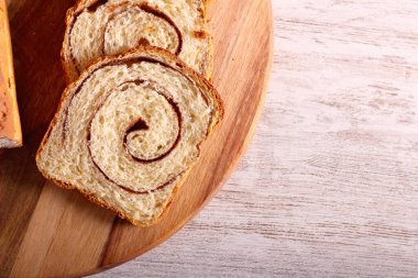 Tarçın kıvrımlı ekmek, tahta üzerinde dilimlenmiş.