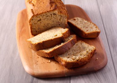 Muz ve haşhaş tohumlu tatlı ekmek, tahta üzerinde dilimlenmiş.