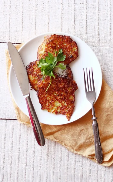 Crêpes de pommes de terre sur une assiette avec des légumes verts et de la crème sure — Photo