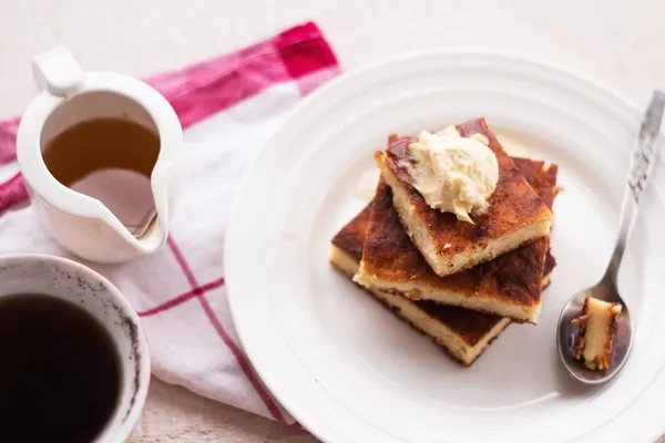 Bitar cheesecake och en kräm, en sked, häll honung, kaffe, ovanifrån, träskivor — Stockfoto