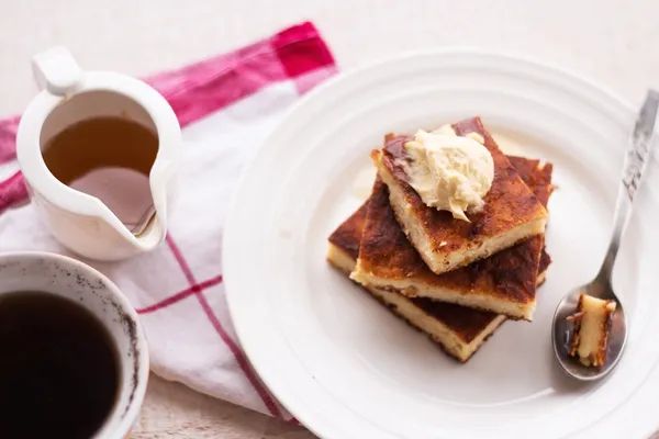 Morceaux gâteau au fromage et une crème, une cuillère, verser le miel, café, vue sur le dessus, planches en bois — Photo