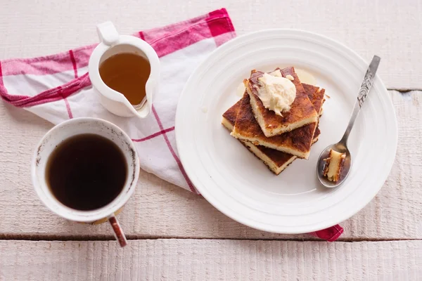 Morceaux gâteau au fromage et une crème, une cuillère, verser le miel, café, vue sur le dessus, planches en bois — Photo