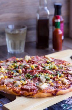 Bütün pizza üzerinde ahşap bir masa, bir bardak soda