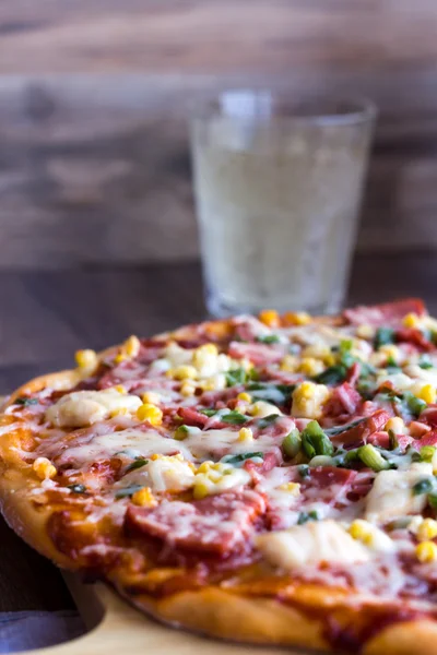 Whole pizza on a wooden board, a glass of soda — Stock Photo, Image