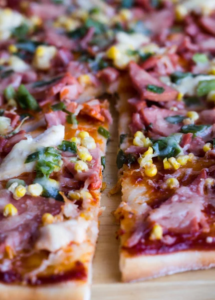 Pizza in Stücke geschnitten mit Wurst, Huhn, Mais und Käse — Stockfoto