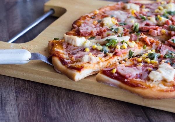 Pizza in Stücke geschnitten mit Wurst, Huhn, Mais und Käse — Stockfoto