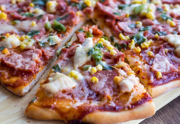 Pizza in Stücke geschnitten mit Wurst, Huhn, Mais und Käse — Stockfoto