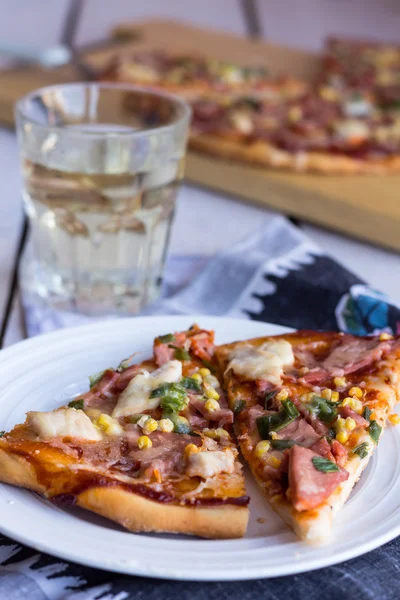 Pizzascheiben auf einem Teller, Tisch und einem Glas Limo — Stockfoto