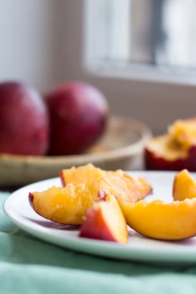 Peaches, juicy slices on white round plate, green napkin — Stock Photo, Image