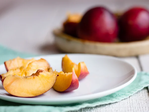 Peaches, juicy slices on white round plate, green napkin — Stock Photo, Image