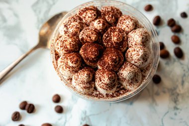Kakaolu taze İtalyan tiramisusu. Beyaz mermer arka planda tiramisu bölümü. Lezzetli. Pişirmeye hazır tiramisu yok. Teslimat. Plastik bardakta yemek servisi..