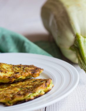kızarmış kabak börek beyaz bir plaka üzerinde dikey olarak, beyaz tahta