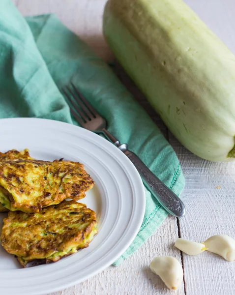 Beignets de courgettes frites sur une assiette blanche, ail, bois blanc — Photo