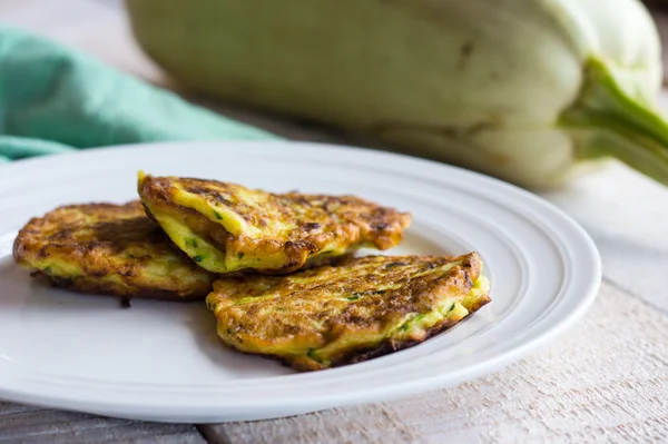 Fried zucchini fritters on a white plate,white wooden background — Stock Photo, Image