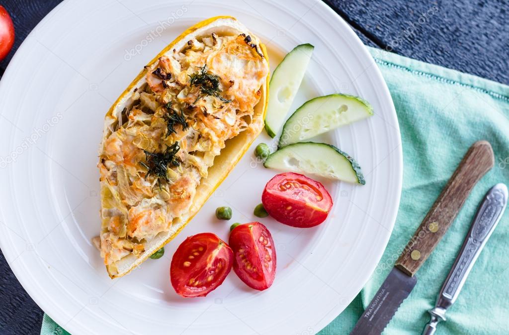 warm stuffed zucchini with chicken and vegetables on a white pla