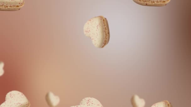 ハート型の様々な直径のバニラマカロンのコレクションは 空を飛んで 自然のベージュの背景に揺れる バレンタイン 結婚式の休日の概念 高品質4K食品映像 — ストック動画