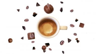 Farklı yönlere ve birçok çapta çikolata parçacıkları ve izole bir zemine düşen koyu kahve çekirdekleri bir fincan kahvenin etrafında uçar ve kıpırdarlar. Sabahın sembolü olarak canlandırma 