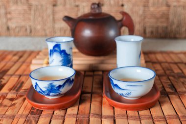 Bambu hasırlı bir masada çay seti. Porselen kaplar