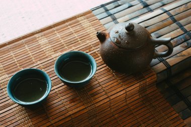 Bambu hasırlı bir masada çay seti. Porselen kaplar